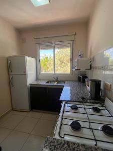 Una cocina con estufa y refrigerador blanco. en Este Apart, en Bahía Blanca