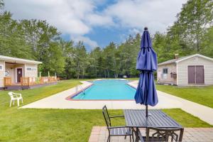 una sombrilla azul sentada en una mesa junto a una piscina en Luxury Pocono Lake House with Private Sunset Beach, en Pocono Summit