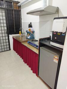 a kitchen with a long counter with red curtains at AK Homestay in Kuala Terengganu