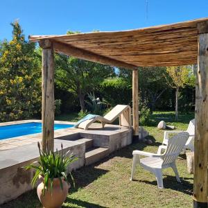 a backyard with a wooden pergola and chairs and a pool at Espacio Nux in Los Árboles