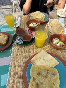a table with plates of food and glasses of orange juice at Riad Le Petit Joyau in Marrakech