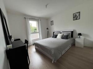a white bedroom with a bed and a window at Appartement Saint-Denis in Saint-Denis
