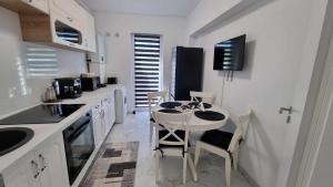 a white kitchen with a small table and chairs at Apartament Ariana Rasnov in Râşnov