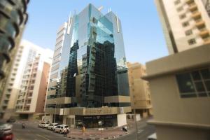 un edificio de cristal alto con coches estacionados frente a él en Glamorous Partition Room in Barsha 1 Near Metro en Dubái