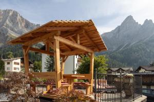 a wooden pergola with a view of mountains at Hotel Panorama in San Martino di Castrozza