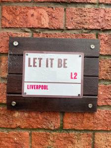 a sign on the side of a brick wall at Let It Be in Liverpool