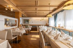 uma sala de jantar com mesas brancas e cadeiras brancas em Hotel Panorama em San Martino di Castrozza
