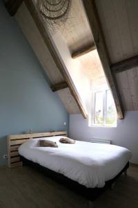 a bedroom with a large white bed with a window at Le Gîte - Le Pressoir in Les Molières
