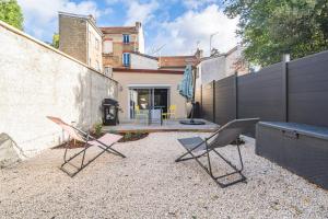 um quintal com duas cadeiras, uma mesa e uma cerca em Art Déco Lesage & Spa em Reims
