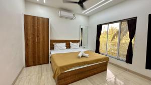 a bedroom with a bed and a large window at Iris Villa - Nagaon Beach in Nagaon