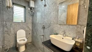 a bathroom with a white sink and a toilet at Iris Villa - Nagaon Beach in Nagaon