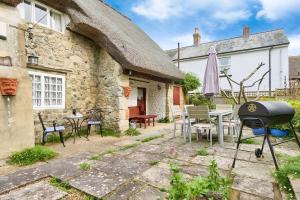 a stone cottage with a grill and a table and chairs at Ye Olde Cottage in Niton
