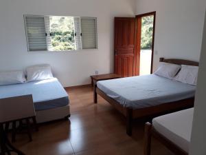 カショエイラ・ド・カンポにあるSítio da Serra em Ouro Preto MGのベッド2台、窓付きのドアが備わる客室です。