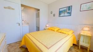 ein Schlafzimmer mit einem Bett mit gelber Bettwäsche und zwei Lampen in der Unterkunft Villa de plain pied avec jardin paysager et piscine in Ars-en-Ré