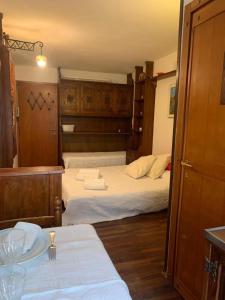 um quarto com uma cama com lençóis brancos e armários de madeira em Casa Neve em Sestriere