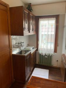 uma cozinha com armários de madeira, um lavatório e uma janela em Casa Neve em Sestriere