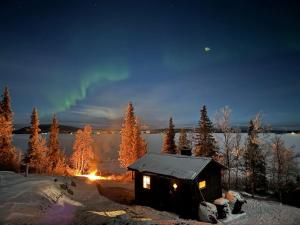 a cabin in the snow with a rainbow in the sky at Northern Light Cabin with sauna by Torneriver in Kiruna