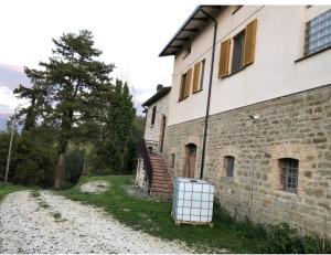 una casa con una strada sterrata accanto a un edificio di I cipressi Gualdo Tadino Uniquement de samedi à samedi a Pieve di Compresseto