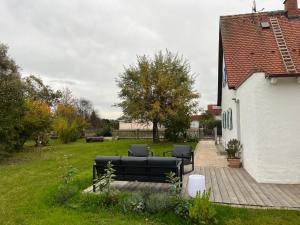 d'une terrasse avec un canapé noir dans la cour. dans l'établissement Home of gmiatlich - Ferien & Wohnen auf Zeit, à Mühldorf