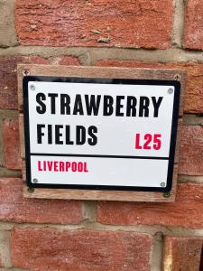 a sign on the side of a brick wall at Strawberry Fields in Liverpool