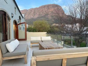 a patio with chairs and a table and a mountain at Calais Guest House in Franschhoek