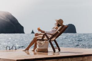 une femme assise sur une chaise sur un quai dans l'établissement Melian Boutique Hotel & Spa, à Pollonia