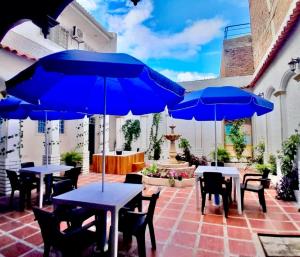 a patio with tables and chairs with blue umbrellas at Hotel Kasaya Real in Santa Marta