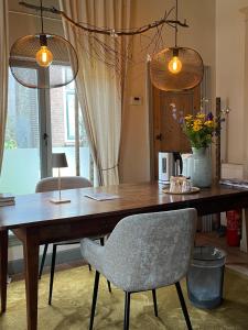 a wooden table with a chair and two lights at B&B De Kamer Hiernaast in Gouda