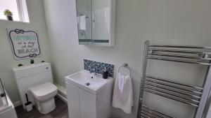 a white bathroom with a toilet and a sink at Southsea Escape - Coastal Holiday Apartment - 2 double bedrooms in Portsmouth +16 photos