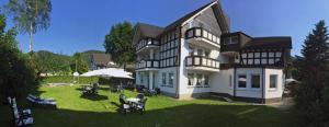 a large black and white house with a yard at Hotel Flurschütz in Lennestadt