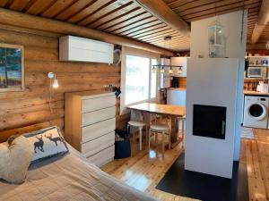 Un dormitorio con una cama y una cocina con una mesa. en Kaupinmaja, Ylläs, Äkäslompolo, Lapland - Log Cabin with Lake and Fell Scenery, en Äkäslompolo