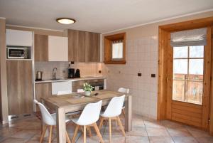 a kitchen with a wooden table and white chairs at Appartamento Trela 3 in Livigno