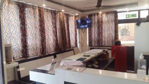 Habitación con cortinas rojas y mesa con TV. en Hotel Shiva Palace haridwar nearby bus and railway station en Haridwār