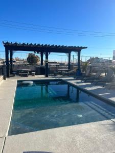 a swimming pool with a pergola and picnic tables at Playas Hotel Suites in Puerto Peñasco