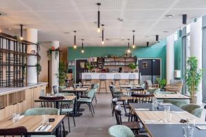 un restaurante con mesas y sillas de madera y una pared verde en All Suites Paris Ouest Colombes, en Colombes