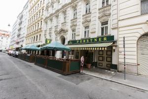 un edificio en una calle con sombrillas en la acera en Carlton Suites, en Viena