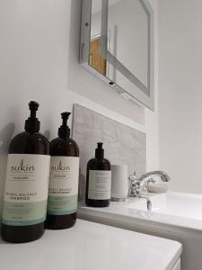 Tres botellas de jabón sentadas en el lavabo del baño en Keeper's Lodge en Rowlands Castle