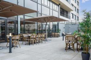 an outdoor patio with tables and chairs and umbrellas at All Suites Paris Ouest Colombes in Colombes
