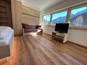 ein Schlafzimmer mit einem Bett, einem TV und einem Sofa in der Unterkunft Appartementhaus Zillertal by PiaundDirk in Finkenberg