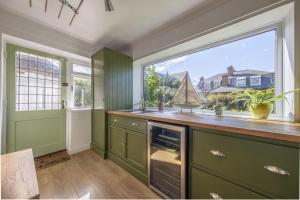 une cuisine avec des placards verts et une grande fenêtre dans l'établissement Porch House, à Hunstanton