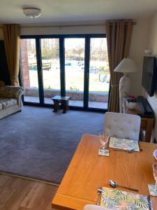 a living room with a wooden table and a living room with a view at Otters End in Dilham