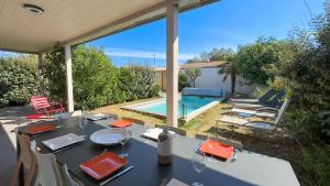 - une table et des chaises en face de la piscine dans l'établissement Superbe villa proche de la mer, à Sainte-Marie de Ré