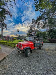 a man sitting in the back of an old red jeep at Hotel Campestre La Tata in Montenegro