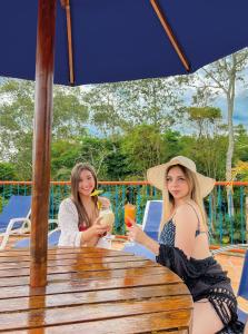 two women sitting at a table under an umbrella at Hotel Campestre La Tata in Montenegro