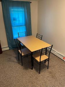 une table en bois avec des chaises et un rideau bleu dans l'établissement Mo Short Term Rentals, à Mount Vernon