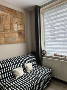 un divano bianco e nero in una stanza con finestra di Les petits nids de Nina 2 a Fosses-La-Ville