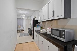 una cocina con armarios blancos y microondas en una encimera en Affordable Cozy Home Away From Home 
