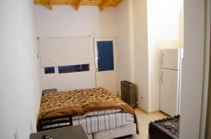 a small bedroom with a bed and a refrigerator at Estudio céntrico para 2 personas in Comodoro Rivadavia
