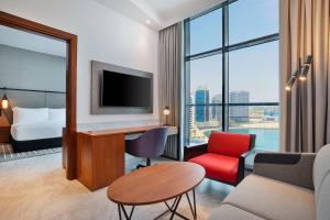 a hotel room with a bed and a desk with a tv at The First Collection Waterfront in Dubai