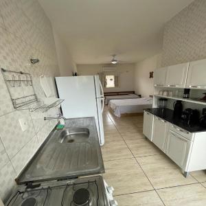 uma cozinha com um lavatório e um frigorífico branco em Carpi Apartamentos Ubatuba em Ubatuba